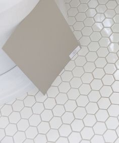 a white toilet sitting next to a gray tile floor in a bathroom with hexagonal tiles on the floor