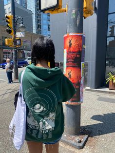 a woman standing next to a pole on the street