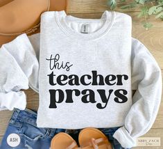 Printed on soft and cozy Gildan brand sweatshirts, our "This Teacher Prays" crewneck sweater is sure to delight any Christian educator! More faith filled shirts are available on our homepage or message me for special requests! https://www.etsy.com/shop/AbbyZachDesigns ----HOW OUR SHIRTS ARE MADE ----  * We use the process of DTG, which stands for direct to garment printing. We partner with a professional printer who applies ink directly into the shirt. (We do not use vinyl.) This gives you bette Pre-shrunk Long Sleeve Sweatshirt For Everyday, Pre-shrunk Long Sleeve Sweatshirt, Everyday Long Sleeve Sweatshirt, Christian Teacher Shirts, Pray Shirt, Brand Sweatshirts, Grandma Names, Bible Teacher, Nana Shirts