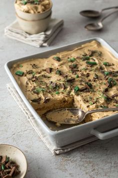 a pan filled with food next to two spoons