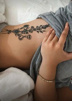 a woman laying on top of a bed covered in tattoos