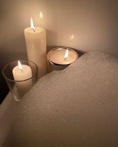 three lit candles sitting on top of a bath tub