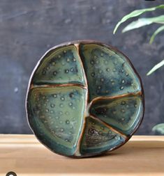 a close up of a vase on a wooden surface with water droplets covering the base