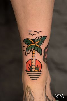 a foot with a palm tree tattoo on it's left side and a bird flying over the top