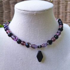 A Witchy And Whimsical Bohemian Glass Choker Necklace. Crafted With Various Shades Of Purple Czech Glass Beading, Faceted Black Czech Glass Beading, Painted Black Wood Beading, And A Striking Diamond-Shaped Black Ceramic Pendant At The Center. Handmade By Me, One Of A Kind. Hypoallergenic Stainless Steel Chain And Clasp. Nickel Free. Total Length: 14.5 Inches Length Of Chain: 13 Inches Extender Length: 1 Inch. If You Require A Longer Extension Chain To Ensure A Proper Fit, Please Let Me Know! Ju Black And Purple Necklace, Purple Necklace With Black Beads, Purple Bohemian Jewelry With Black Beads, Bohemian Purple Jewelry With Black Beads, Purple Spiritual Crystal Necklace For Festivals, Spiritual Purple Crystal Necklace For Festivals, Purple Necklace With Black Beads For Gift, Gift Purple Necklace With Black Beads, Handmade Purple Crystal Necklaces For Festival