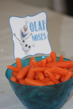 a bowl filled with carrots sitting on top of a table next to a sign