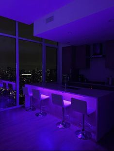 three bar stools are illuminated in purple light