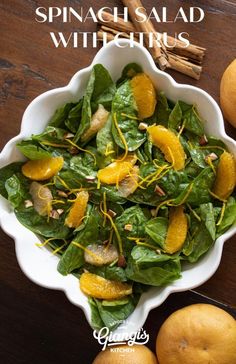 spinach salad with oranges in a white bowl on a wooden table next to cinnamon sticks