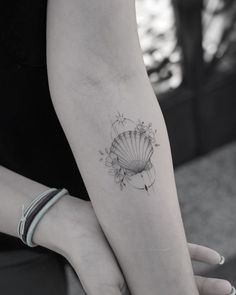 a woman's arm with a shell tattoo on it