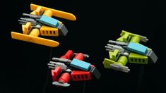 three different colored plastic toys on sticks with handles and clips in the shape of spaceships