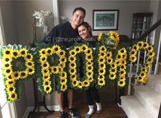 a man and woman are standing in front of sunflowers that spell out the word prom