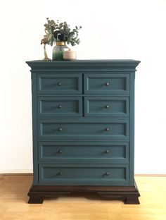 a blue dresser sitting on top of a hard wood floor next to a white wall