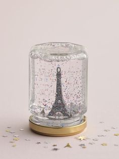 the eiffel tower in a glass jar is surrounded by confetti and stars