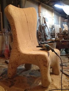 a wooden chair sitting on top of a floor next to a pile of wood planks