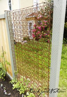 a garden gate with vines and flowers growing on the side of it in front of a house