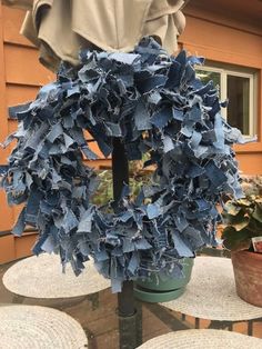 a blue wreath sitting on top of a table next to a potted plant in front of a house