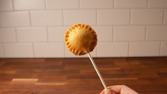 a hand holding a pastry on a toothpick