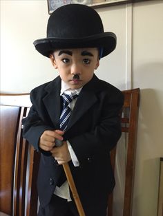 a young boy dressed up in a suit and tie with a top hat on his head