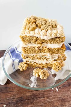 three layers of cake sitting on top of a glass plate with white frosting and walnuts