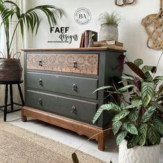 an old dresser is painted dark green and decorated with plants