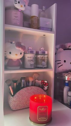 a hello kitty candle sitting on top of a table next to a shelf filled with items