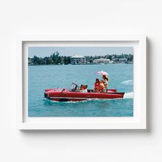 two women in a red speedboat with an umbrella on the back, and another woman holding a pink umbrella over her head