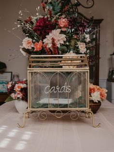 a table topped with a glass box filled with flowers