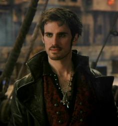 a man in a leather jacket standing next to a pirate ship