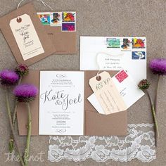 the wedding stationery is laid out on the ground with purple flowers in front of it