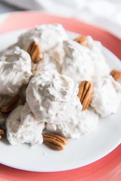 a white plate topped with ice cream and pecans on top of a pink table cloth