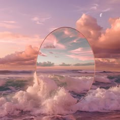 a round mirror sitting on top of a beach next to the ocean under a cloudy sky