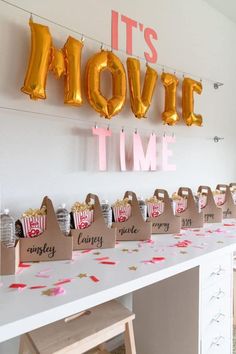 there are many bags on the table and balloons in the air above them that say it's movie time