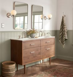 a bathroom vanity with two mirrors above it and a rug on the floor next to it