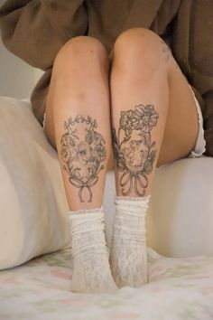 a woman with tattoos on her legs sitting on a bed