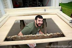 a man sitting in front of a window made out of wooden planks with his mouth open