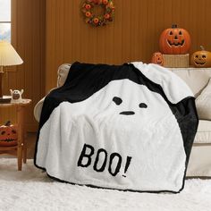 a black and white blanket with the word boo on it is sitting on a couch