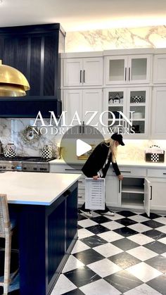 a woman standing in the middle of a kitchen with black and white checkered flooring