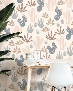 a desk with a chair, potted plant and wallpaper