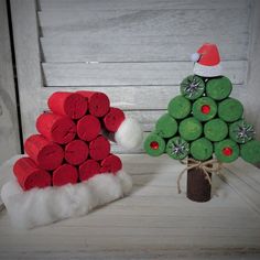 two christmas trees made out of wine corks on a white wooden table with santa hat