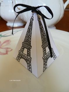 an ornament shaped like the eiffel tower is tied with a black ribbon