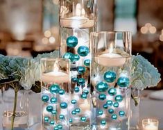 the centerpieces are filled with candles and blue balls in glass vases, along with white hydrangeas