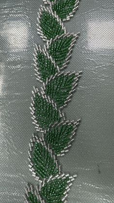 a close up of a green and silver fabric with leaves on it's side