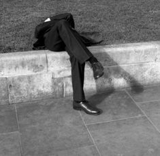 a man sitting on the side of a stone wall with his head in his hands