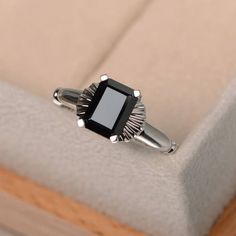 a black diamond ring sitting on top of a white cushion