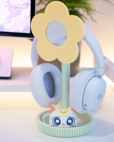 headphones are sitting on a stand in front of a computer monitor with a flower