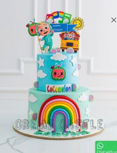 a multi layer cake decorated with cartoon characters and rainbows on the bottom tier, in front of a white wall