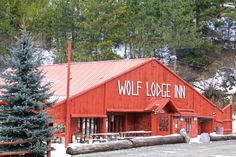 a red building with white writing on the side and trees in front of it that says wolf lodge inn