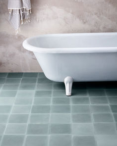 a white bath tub sitting on top of a bathroom floor next to a towel rack