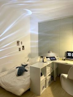 a room with a bed, desk and computer monitor on top of the desk is covered in plastic sheeting