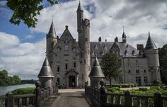 an old castle with towers and turrets on the front entrance is seen through a gate